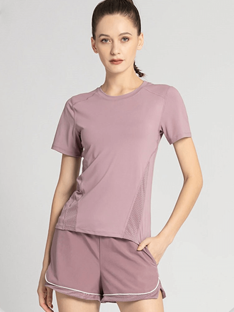 Woman wearing a pink quick-dry athletic t-shirt with mesh back, ideal for yoga, offering comfort and mobility.